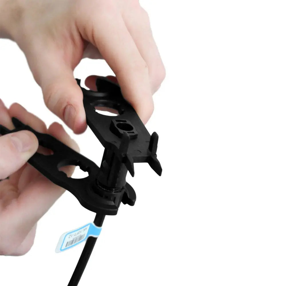 Hands gripping a wired solar connector with two Renogy MC4 assembly tools